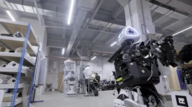 Fabrika Robotlar, modern robot gelişmeler üretimi için. Demonte robot tebrik elinde ve dansları atölye dalgalar. Mühendisler yürüyüş içinde belgili tanımlık geçmiş.