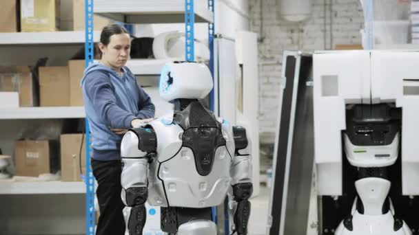 Fabrik för tillverkning av robotar. Forskare reflekterar på enheten av roboten. Ställer upp och gör justeringar, skapar en ny robot — Stockvideo
