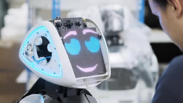 Fabrik für die Produktion von Robotern. Ingenieur passt die Tastatur an. erstellt Software für den neuen Roboter — Stockvideo