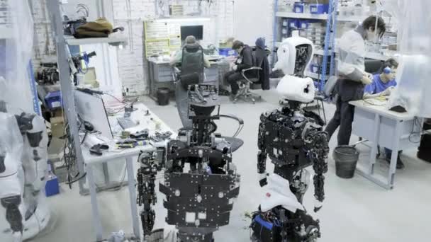 Завод по производству роботов, современные роботизированные разработки. Группа молодых инженеров создает новых современных роботов. Роботы разбираются в мастерской . — стоковое видео