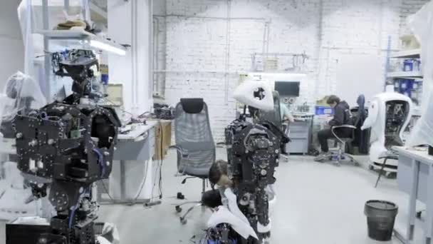 Fábrica para la producción de robots, desarrollos robóticos modernos. Un grupo de jóvenes ingenieros crea nuevos robots modernos. Los robots se desmontan en la tienda . — Vídeos de Stock