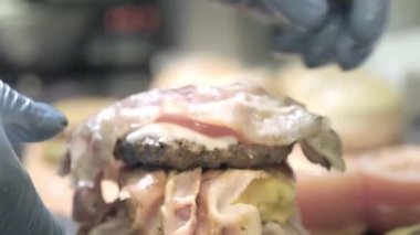 Eller hamburger hazırlıyor. Sokak gıda festivalinde bir sığır Burger hazırlama görünümü yakın. Aşçı restoranda hızlı yemek hazırlar.