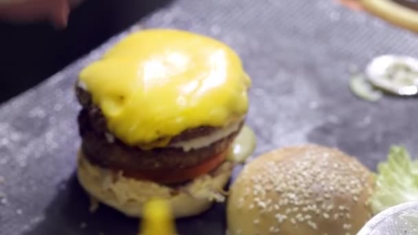 Hände bereiten einen Hamburger zu. Nahaufnahme der Zubereitung eines Rindfleisch-Hamburgers beim Streetfood-Festival. Koch bereitet Fast Food im Restaurant zu. — Stockvideo