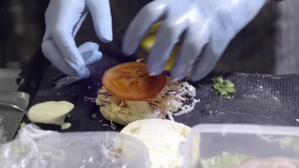 Mãos a preparar um hambúrguer. Vista de perto da preparação de um hambúrguer de carne no festival de comida de rua. Chef prepara fast food no restaurante . — Vídeo de Stock