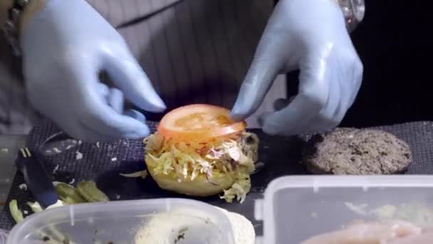 Mains préparant un hamburger. Vue rapprochée de la préparation d'un hamburger de bœuf au festival de la cuisine de rue. Chef prépare la restauration rapide au restaurant . — Video