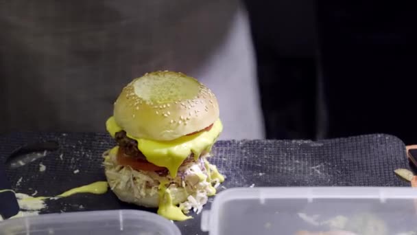 Mani che preparano un hamburger. Vista da vicino di preparare un hamburger di manzo al festival street food. Lo chef prepara fast food al ristorante . — Video Stock