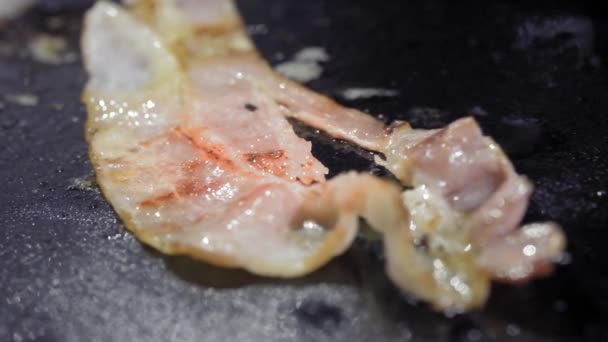 Κοντινό πλάνο του μια φέτα μπέικον τηγανητό σε μια καυτή σχάρα — Αρχείο Βίντεο