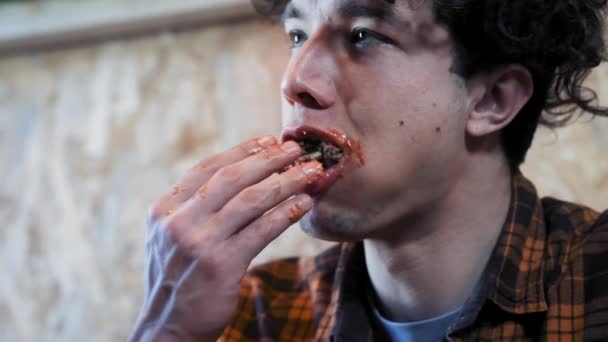 Молодой человек уродлив и грубо ест сэндвичи. Ест фаст-фуд. Концепция общества ожирения и плохого питания. смешное видео . — стоковое видео
