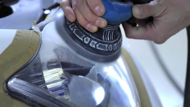 Headlight Polishing, processing of car lights. A car service worker polishes the headlight of a passenger car with a special polishing tool. Professional polishing — Stock Video