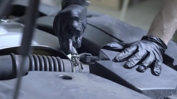 Trabajador de servicio del coche desenrosca los tornillos debajo de la capucha del coche. Repara el coche, comprueba el rendimiento — Vídeos de Stock