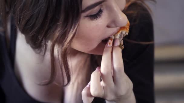 Chica joven y sexy come comida rápida en un café. Primer plano. Muerde un trozo de pollo frito. El concepto de snack rápido y la sociedad de la obesidad — Vídeo de stock