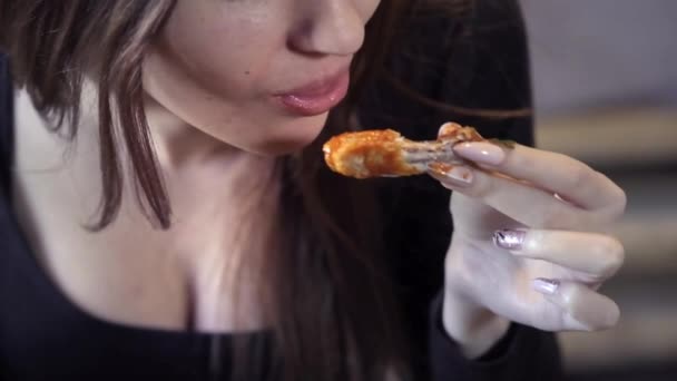 Sexy junges Mädchen isst Fast Food in einem Café. Nahaufnahme. beißt ein Stück gebratenes Huhn ab. das Konzept der Gesellschaft für schnelle Snacks und Fettleibigkeit — Stockvideo