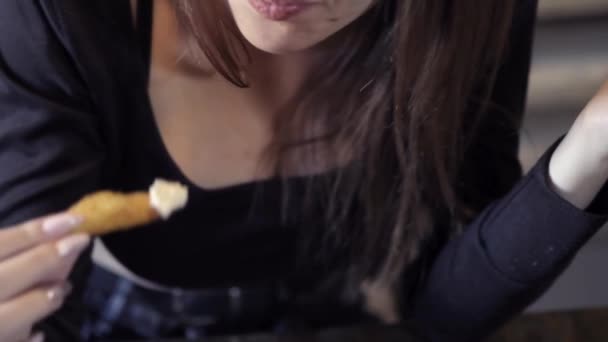 Sexy mladá dívka jí v kavárně rychlá jídla. Close-up. Kousni si hranolky. Koncepce rychlé občerstvení a společnosti pro obezitu. — Stock video