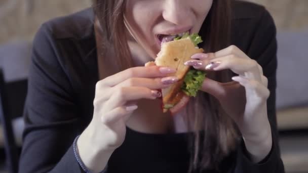 Seksowna młoda dziewczyna zjada sedvich. Zbliżenie. Koncepcja szybkiego społeczeństwa przekąskę i otyłość. Żywność dla freelancerów — Wideo stockowe