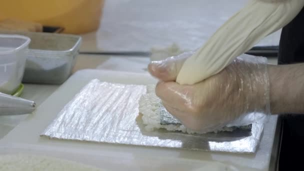 Nahaufnahme. Kochen Sushi-Koch bereitet Brötchen in der Küche. Dreht den Reis und Nori, schneidet das Werkstück. Verwendet japanische Werkzeuge. — Stockvideo