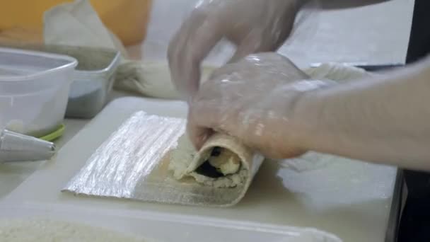 Nahaufnahme. Kochen Sushi-Koch bereitet Brötchen in der Küche. Dreht den Reis und Nori, schneidet das Werkstück. Verwendet japanische Werkzeuge. — Stockvideo