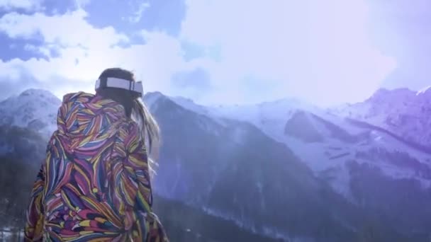 Hermosa joven con gafas de esquí. Sonríe y obtiene placer de las vacaciones de invierno. Listo para esquiar o snowboard. Vacaciones de invierno en un resort de snowboard. Situado en la cima de la montaña . — Vídeo de stock