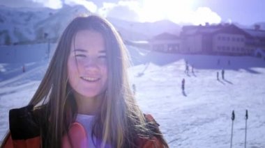 Güzel genç kız kayak gözlükleri giyiyor. Gülümsüyor ve kış tatilinden zevk alır. Kayak veya snowboard için hazır. Snowboard beldesinde kış tatili. Dağın tepesinde yer alan.