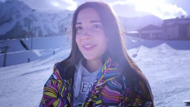 Hermosa joven con gafas de esquí. Sonríe y obtiene placer de las vacaciones de invierno. Listo para esquiar o snowboard. Vacaciones de invierno en un resort de snowboard. Situado en la cima de la montaña . — Vídeos de Stock