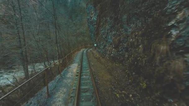 Старый поезд или локомотив едет по узкококолейной железной дороге в узком ущелье. Поезд идет по дну ущелья, рядом с горной рекой . — стоковое видео