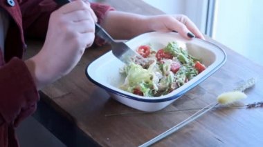 Güzel bir genç kadın Sezar salatası demir bir kase içinde karışık yiyor. Sokak Yemekleri, sağlıksız gıda. Obezite ve sağlıklı beslenme sorunları. Close. Yavaş hareket