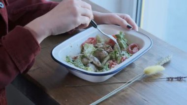 Güzel bir genç kadın Sezar salatası demir bir kase içinde karışık yiyor. Sokak Yemekleri, sağlıksız gıda. Obezite ve sağlıklı beslenme sorunları. Close. Yavaş hareket