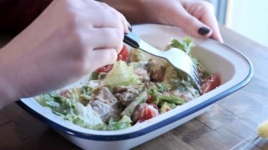 Güzel bir genç kadın Sezar salatası demir bir kase içinde karışık yiyor. Sokak Yemekleri, sağlıksız gıda. Obezite ve sağlıklı beslenme sorunları. Close. Yavaş hareket