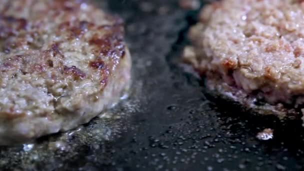 Matlagning en hamburgare, biff eller biff. På en varm spis, en pommes frites kött i ett professionellt kök. Kocken kontrollerar köttets beredskap och förvandlar köttbit över. Makro ram — Stockvideo