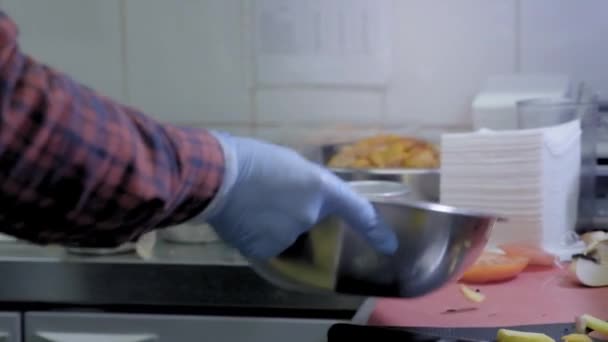 De kok verlaagt in een kokende olie friteuse met frietjes. Metalen doos kan voor rauwe aardappel. De keuken van een fastfoodrestaurant. Het maken van chips. Rauwe aardappelchips in RVS kom. — Stockvideo