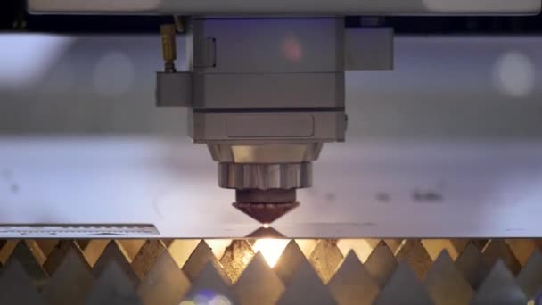 금속 절단. 스파크는 레이저에서 날아오입니다. 스파크가 있는 산업용 레이저 커터. 프로그래밍 된 로봇 헤드는 거대한 금속 온도 시트의 도움으로 절단됩니다.. — 비디오