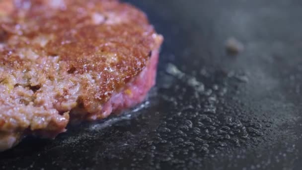 Готуємо гамбургер, пиріг або стейк. На гарячій плиті готують м'ясо на професійній кухні. Кухар перевіряє готовність м'яса і перевертає шматочок м'яса. Рамка макросів — стокове відео