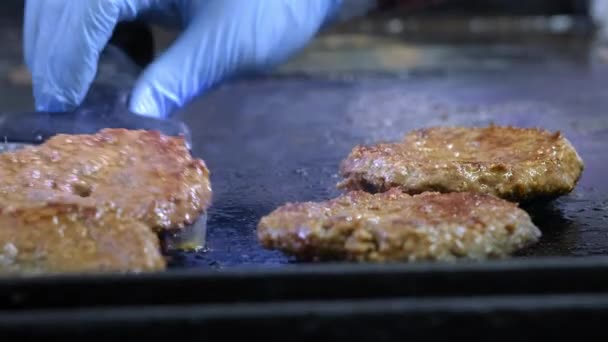 Gotowanie Hamburger, Patty lub stek. Na gorącym piecu, smażone mięso z frytkami w profesjonalnej kuchni. Kucharz sprawdza gotowość mięsa i zamienia kawałek mięsa. Ramka makro — Wideo stockowe
