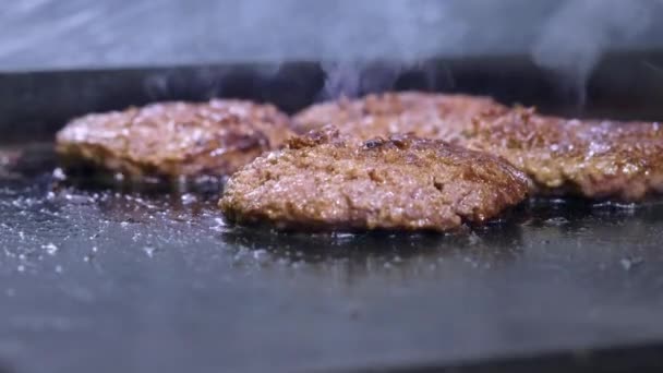 Memasak hamburger, patty atau steak. Di atas kompor panas, memasak daging goreng di dapur profesional. Juru masak memeriksa kesiapan daging dan membalik potongan daging. Bingkai makro — Stok Video