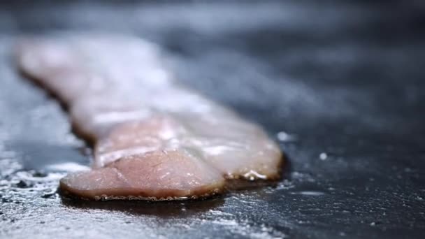 Gros plan de tranches de bacon grillées sur un gril chaud. Un cuisinier dans une cuisine professionnelle frites et tourne tranches de bacon — Video