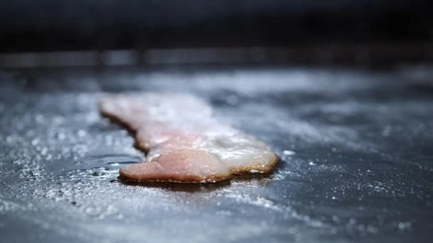 Primer plano de rodajas de tocino a la parrilla en una parrilla caliente. Un cocinero en una cocina profesional fritas y se convierte en rodajas de tocino — Vídeos de Stock