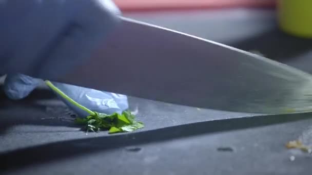 En professionell i köket klipper ett gäng persilja med en stor kniv. Rätt näring och välbefinnande. Förbered och hacka frodig grönska för vegan. Äta hemma. Livsmedelsindustrin. Närbild. — Stockvideo