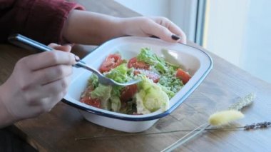 Güzel bir genç kadın, demir bir kapta karışık Sezar salatası yiyor. Sokak yemekleri, sağlıksız abur cubur. Obezite ve sağlıklı beslenme sorunları. Close.