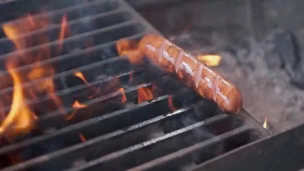 Smakelijke sappige worstjes grillen over een vuur. Cook man bereidt worstjes op de grill. Gooit op de grill en flips. Familie zomer vakantie. — Stockvideo