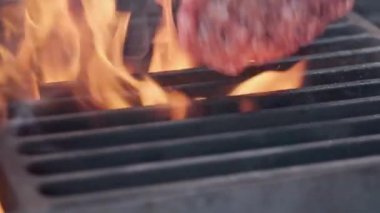 Hamburger pişirmek. Izgara üzerinde Sığır veya domuz pirzolası ızgara. Cook adam ızgara bir burger köftesi hazırlanıyor. Izgara üzerine koydu ve overturned flatware. Aile yaz tatili. Yavaş çekim