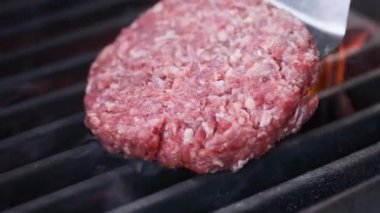 Hamburger pişirmek. Izgara üzerinde Sığır veya domuz pirzolası ızgara. Cook adam ızgara bir burger köftesi hazırlanıyor. Izgara üzerine koydu ve overturned flatware. Aile yaz tatili. Yavaş çekim