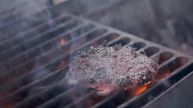Hamburger pişirmek. Izgara üzerinde Sığır veya domuz pirzolası ızgara. Cook adam ızgara bir burger köftesi hazırlanıyor. Izgara üzerine koydu ve overturned flatware. Aile yaz tatili. Yavaş çekim