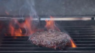 Hamburger pişirmek. Izgara üzerinde Sığır veya domuz pirzolası ızgara. Cook adam ızgara bir burger köftesi hazırlanıyor. Izgara üzerine koydu ve overturned flatware. Aile yaz tatili. Yavaş çekim