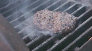 Hamburger pişirmek. Izgara üzerinde Sığır veya domuz pirzolası ızgara. Cook adam ızgara bir burger köftesi hazırlanıyor. Izgara üzerine koydu ve overturned flatware. Aile yaz tatili. Yavaş çekim