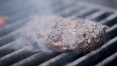 Hamburger pişirmek. Izgara üzerinde Sığır veya domuz pirzolası ızgara. Cook adam ızgara bir burger köftesi hazırlanıyor. Izgara üzerine koydu ve overturned flatware. Aile yaz tatili. Yavaş çekim