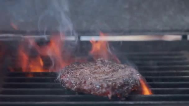 Cocinar hamburguesa. Carne de res o chuleta de cerdo a la parrilla en rejilla. Cocinero preparando una hamburguesa a la parrilla. Se acostó en la parrilla y volcó la vajilla. Vacaciones familiares de verano. Movimiento lento — Vídeos de Stock