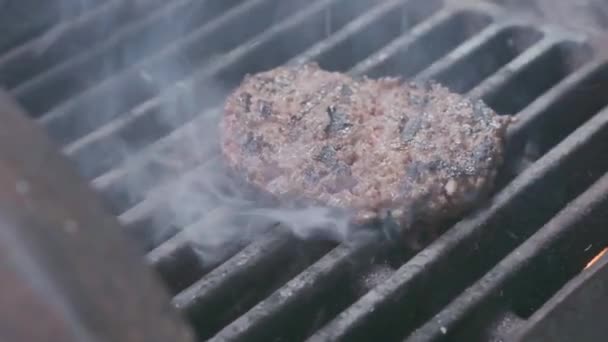 Gotowanie Hamburger. Wołowina lub wieprzowina kotlet grillowanie na siatce. Cook człowiek przygotowuje Patty Burger na grilla. Ułożona na grillu i przewrócone sztućce. Rodzinne wakacje lato. Zwolnionym — Wideo stockowe