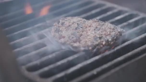 Cocinar hamburguesa. Carne de res o chuleta de cerdo a la parrilla en rejilla. Cocinero preparando una hamburguesa a la parrilla. Se acostó en la parrilla y volcó la vajilla. Vacaciones familiares de verano. Movimiento lento — Vídeos de Stock