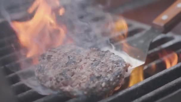 Hamburger pişirmek. Izgara üzerinde Sığır veya domuz pirzolası ızgara. Cook adam ızgara bir burger köftesi hazırlanıyor. Izgara üzerine koydu ve overturned flatware. Aile yaz tatili. Yavaş çekim — Stok video