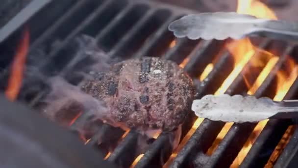 A cozinhar hambúrguer. Carne ou costeleta de porco grelhados na grelha. O cozinheiro está a preparar um hambúrguer na grelha. Deitado na grelha e derrubado flatware. Férias em família. Movimento lento — Vídeo de Stock