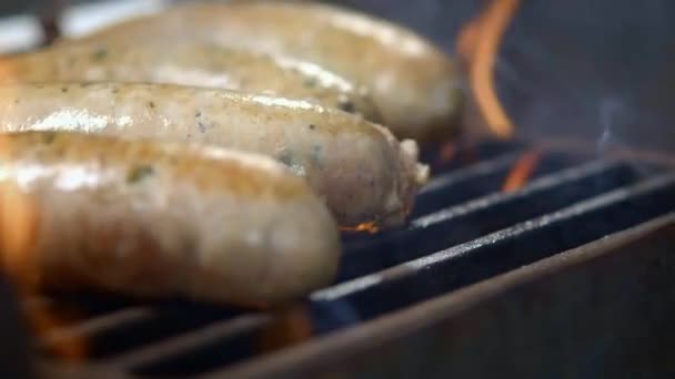 Cozinhe preparando salsichas frescas suculentas grelhadas. Assado a arder. Férias em família. Close-up . — Vídeo de Stock